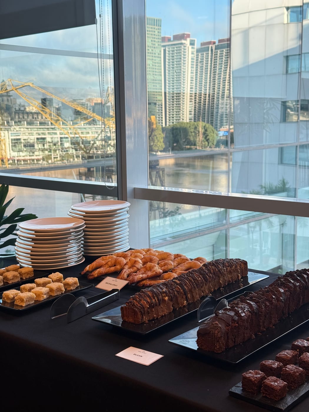 Brochettes, medialunas y brownies en un buffet de evento con vista a Puerto Madero