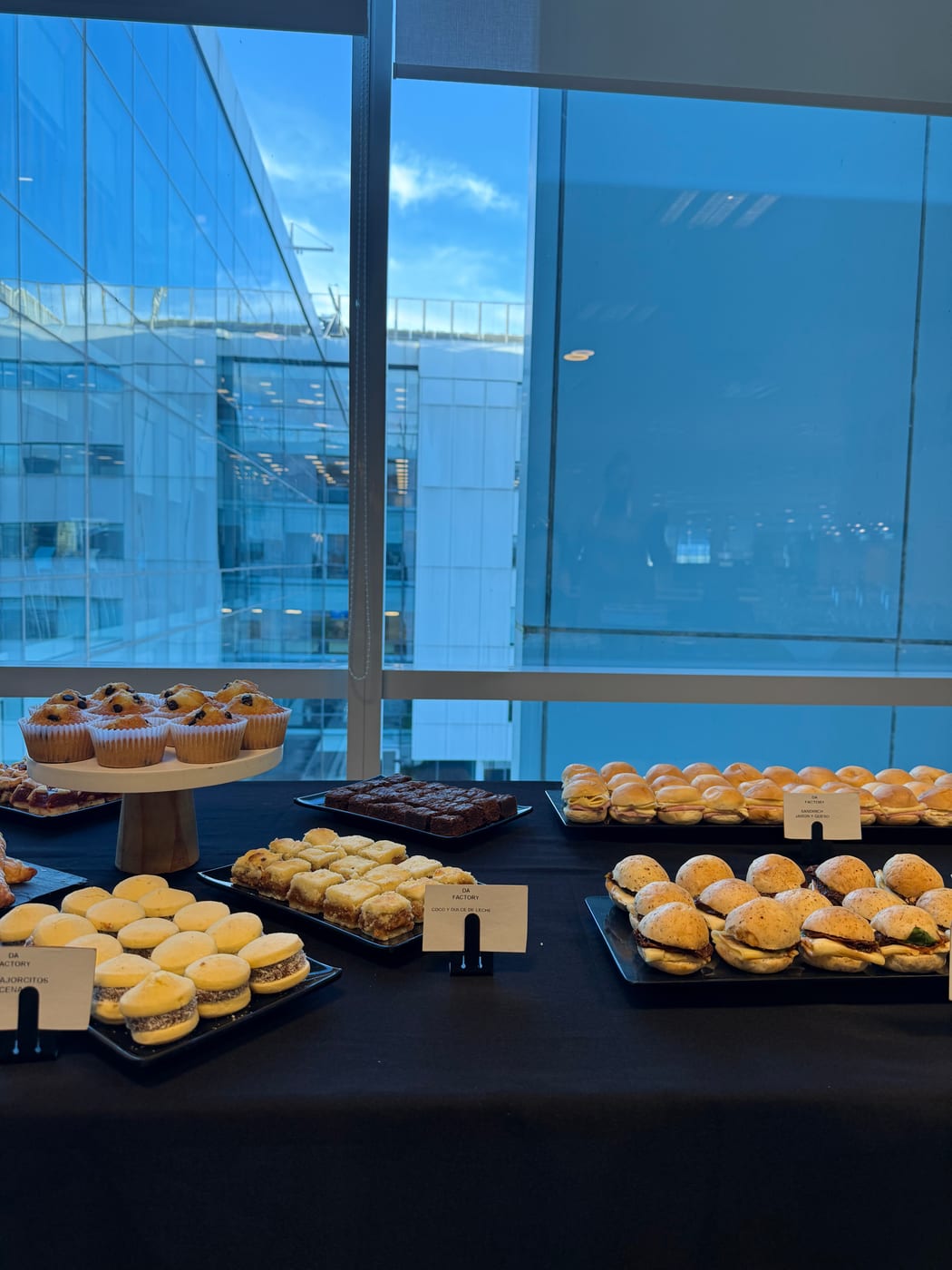 Bandejas de medialunas, sándwiches y muffins para un desayuno de oficina