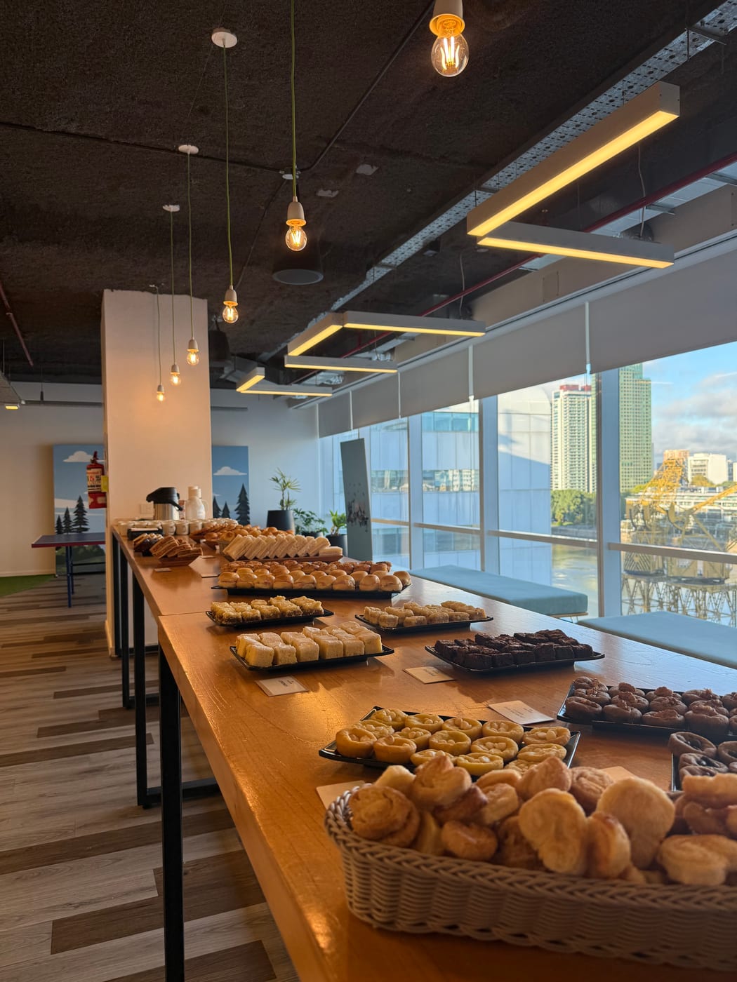 Buffet de desayuno con canastos de pan y facturas frente a un ventanal con vista a Puerto Madero