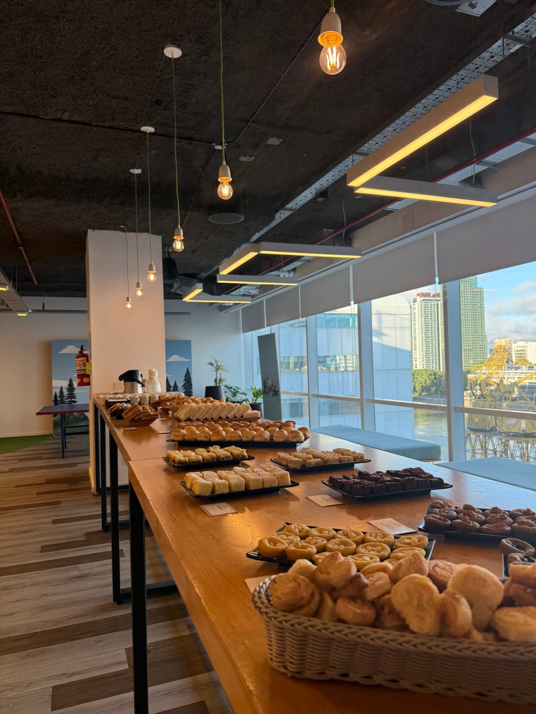 Buffet de desayuno con panes y medialunas servido en un salon corporativo luminoso