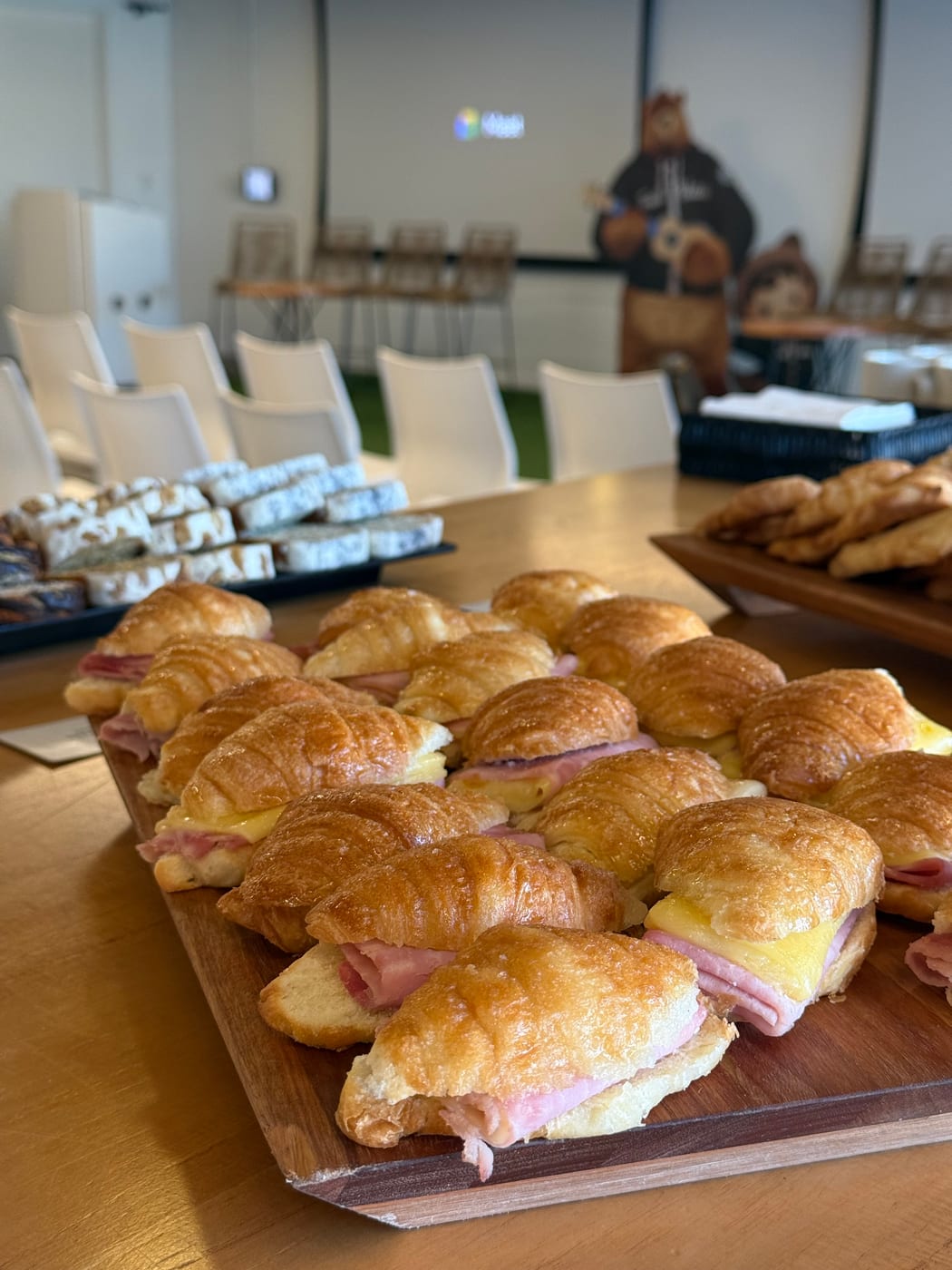 Bandeja de croissants de jamon y queso sobre tabla de madera en un evento