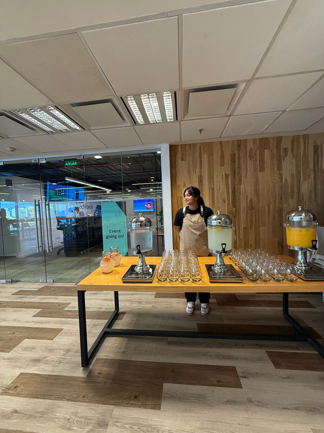 Estacion de bebidas con dispensadores de jugo y vasos atendida por personal de catering