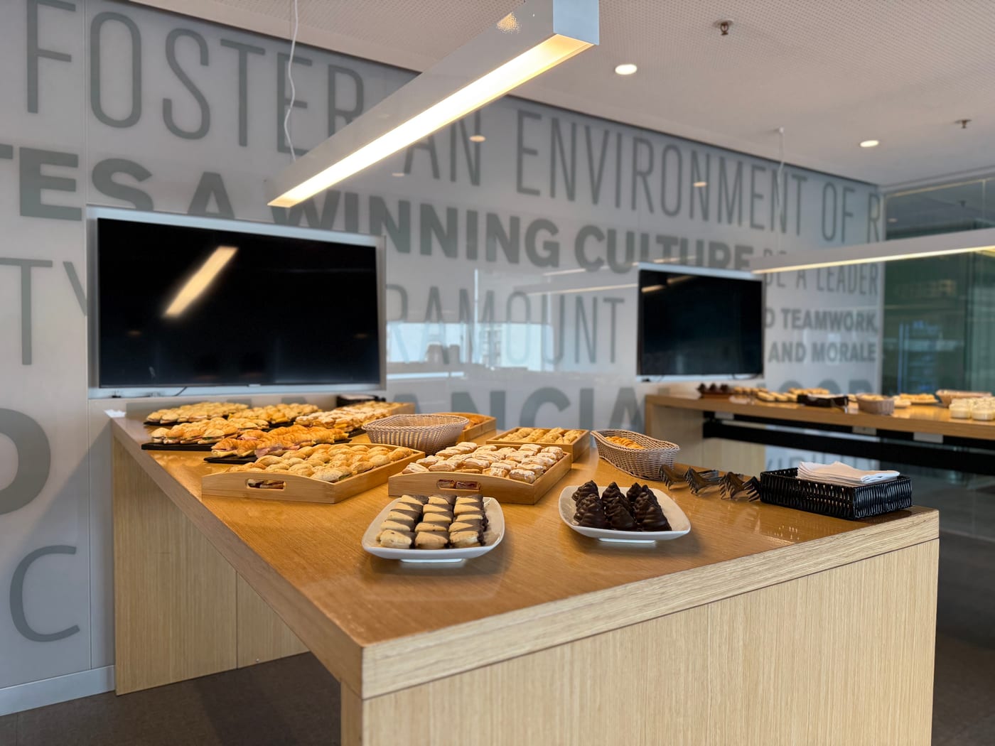 Barra de coffee break con facturas, masas finas y bombones en una sala de reuniones corporativa