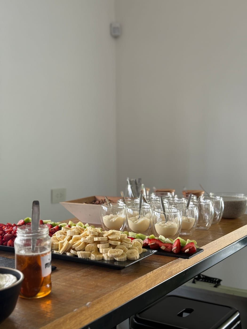Mesa de merienda con copas de postre, banana, frutillas y kiwi