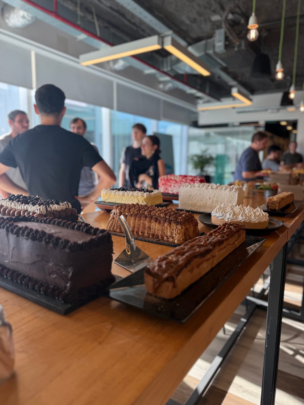 Mesa dulce de evento con tortas y postres variados en un espacio de oficina