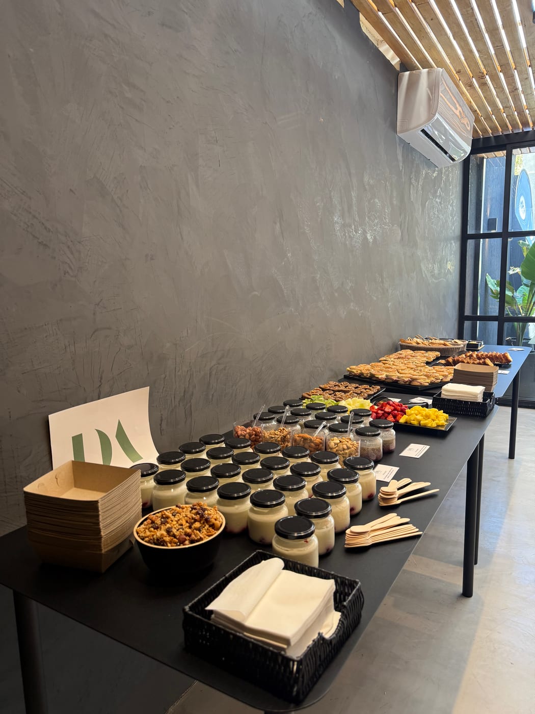 Barra de coffee break con postres en vasos, cereales y servilletas para un evento