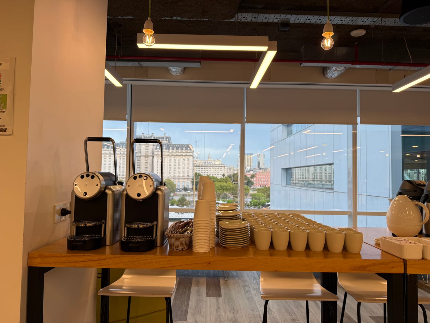 Estacion de cafe con maquinas y tazas para un coffee break corporativo con vista a la ciudad