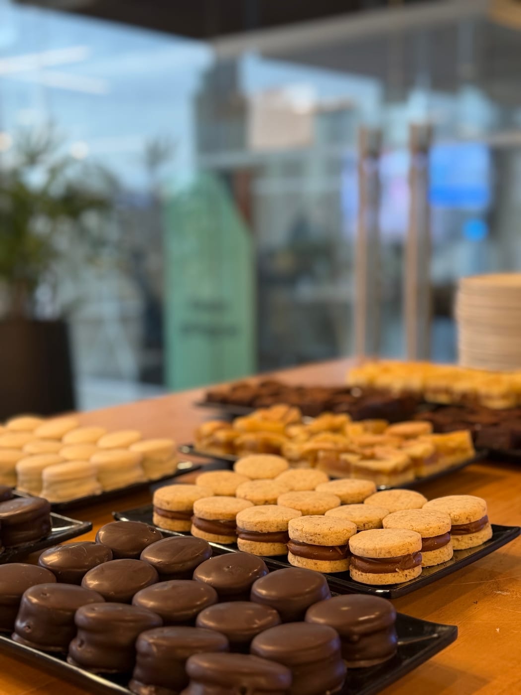 Mesa de coffee break con alfajores de chocolate y de maicena, brownies y pasteles surtidos