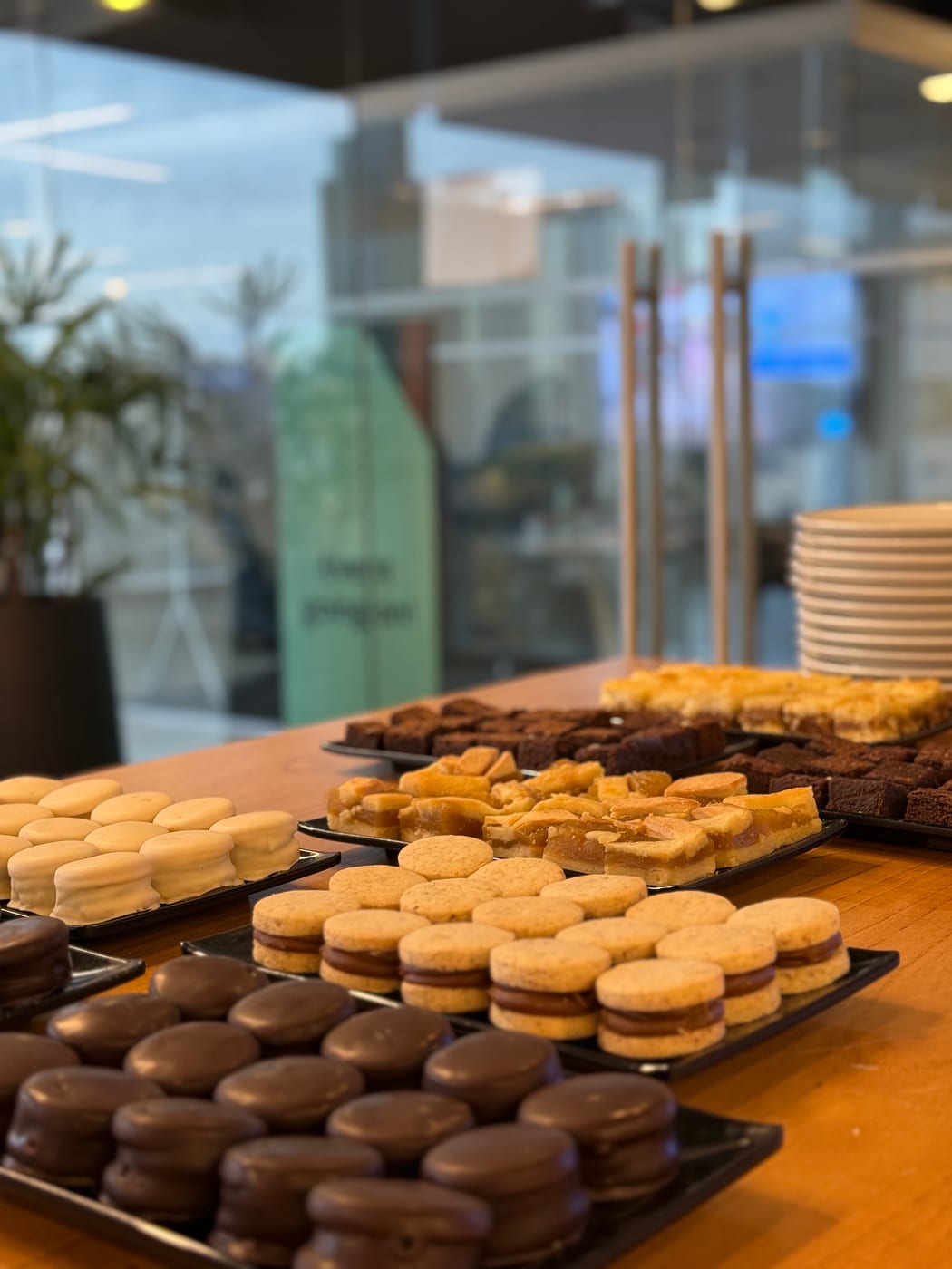 Bandejas de alfajores de chocolate, alfajores blancos y brownies en una mesa de coffee break corporativo