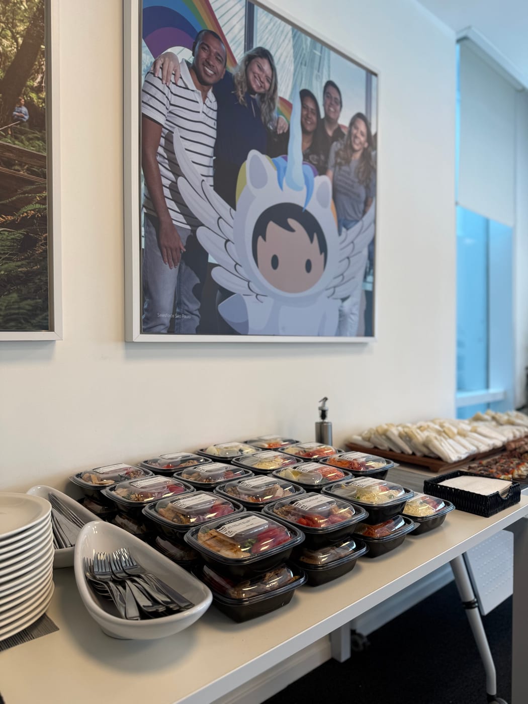 Mesa de almuerzo corporativo con viandas individuales en bandejas y cubiertos listos para servir