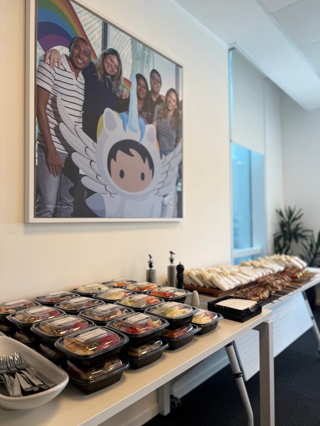 Mesa de catering corporativo con viandas individuales, wraps y brochettes servidas en oficina