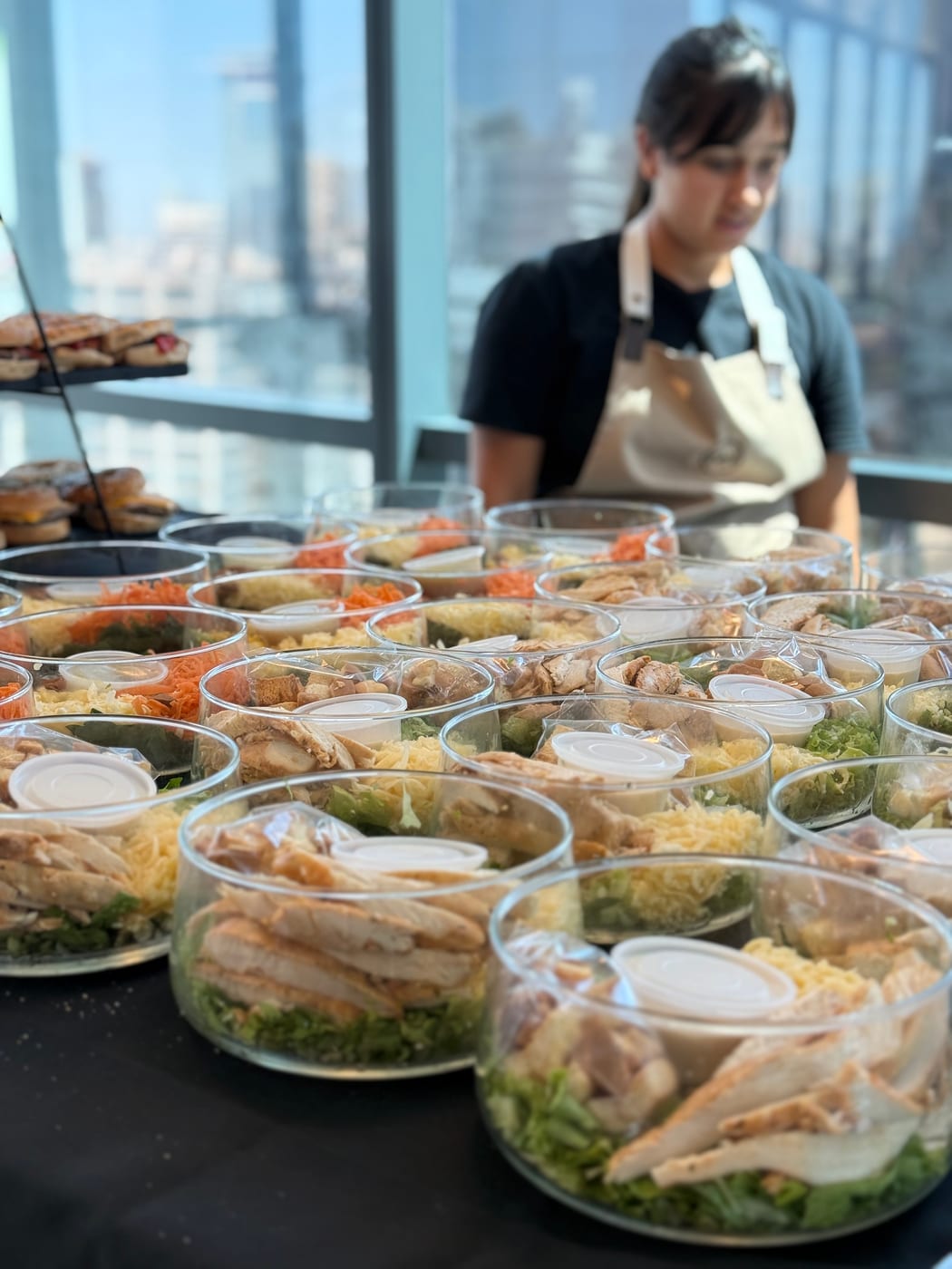 Mesa de ensaladas individuales con pollo y sandwiches para almuerzo corporativo