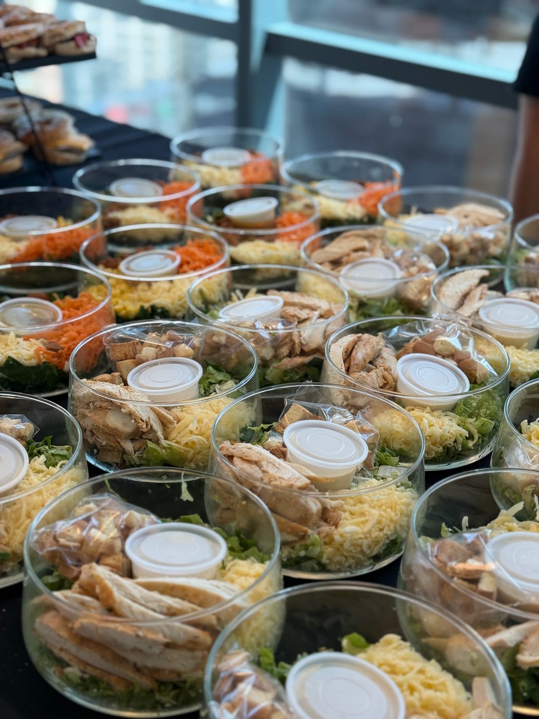 Ensaladas individuales con pollo, queso y zanahoria dispuestas para servir en un evento