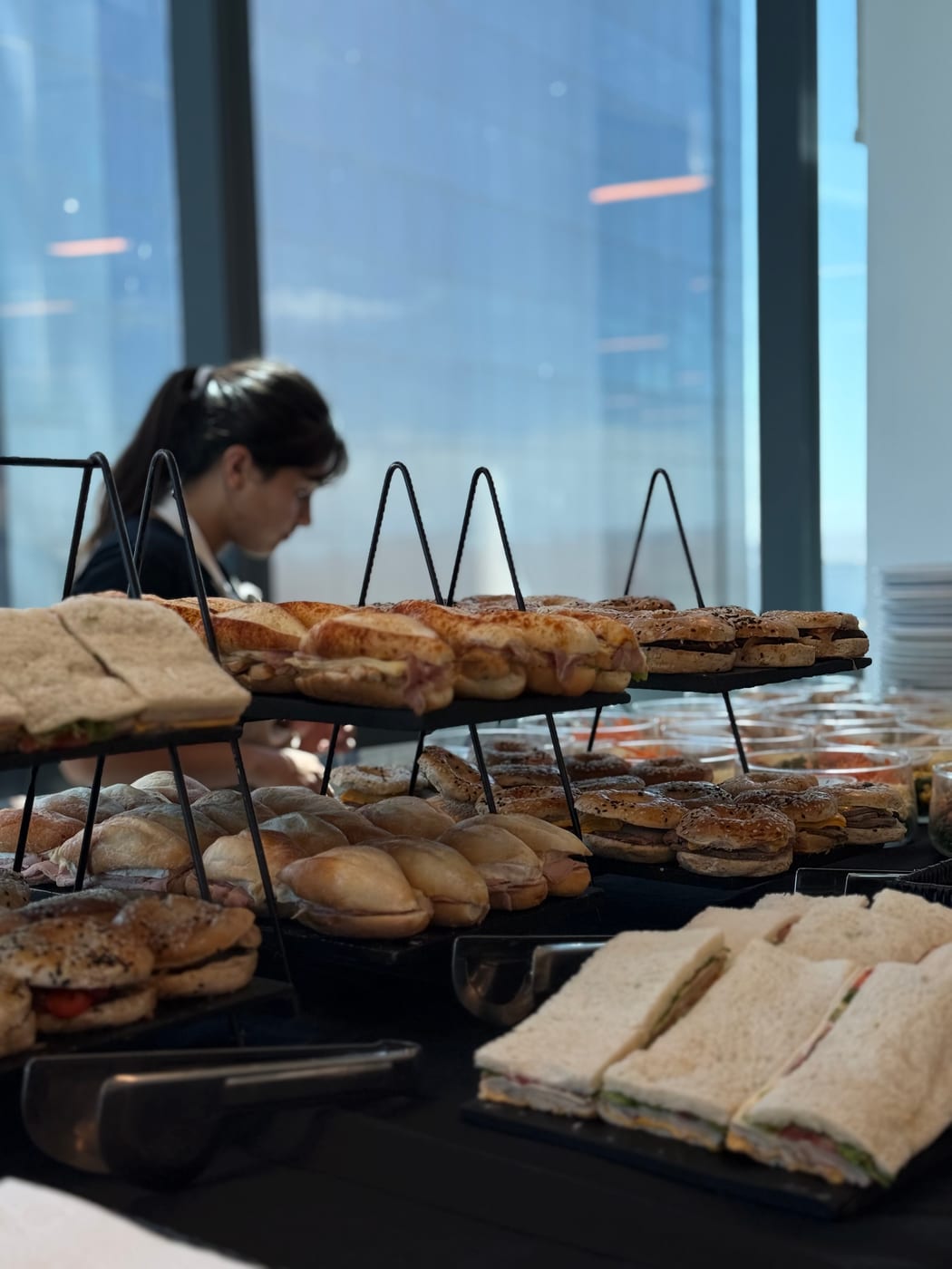 Buffet de sandwiches surtidos servidos en gradas junto a ventanal