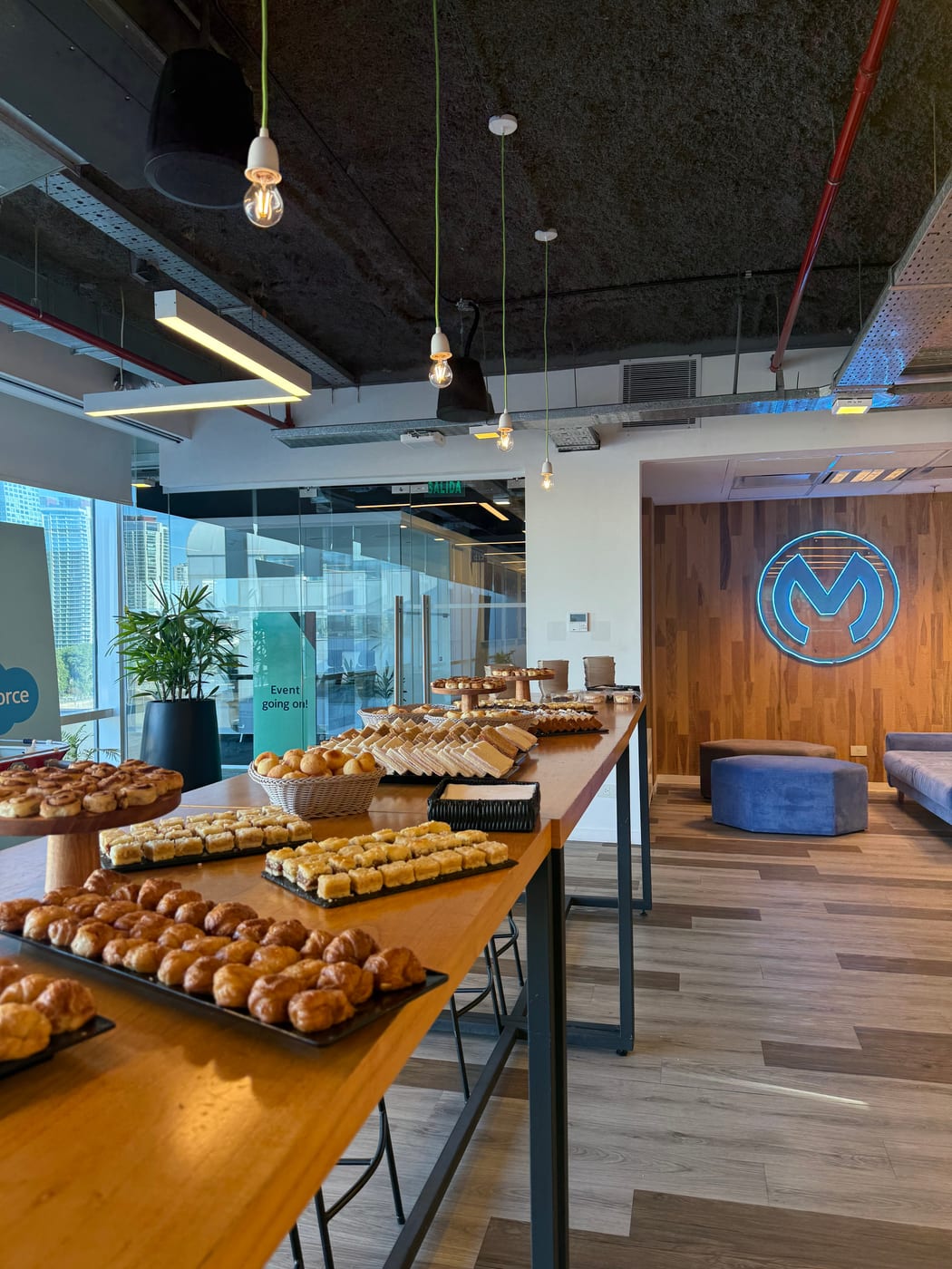 Barra de desayuno corporativo con medialunas, facturas y panificados en un evento de empresa