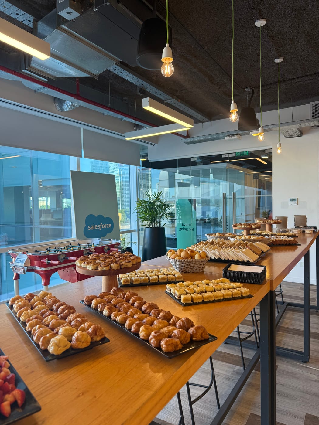 Barra de desayuno completa con medialunas, facturas y frutas en un evento de empresa