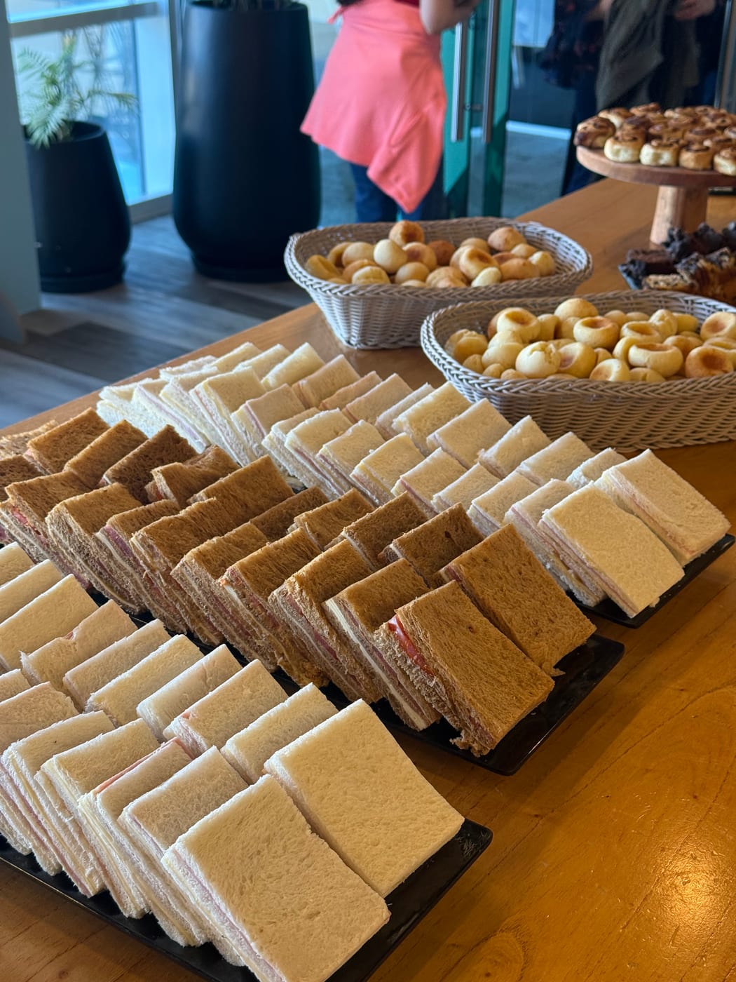 Mesa de desayuno corporativo con sandwiches de miga y canastas de pan de pancho