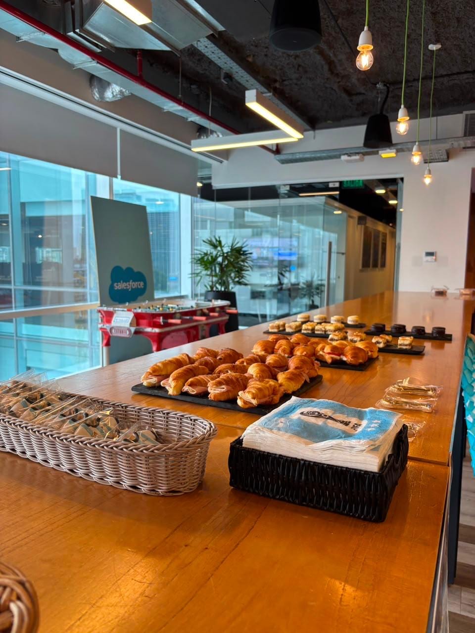 Buffet de desayuno con medialunas y sandwiches en una oficina moderna