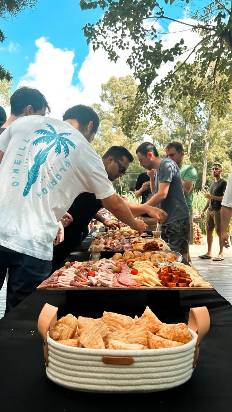 Mesa de recepcion al aire libre con tabla de fiambres, embutidos y panes surtidos servida a los invitados en un evento
