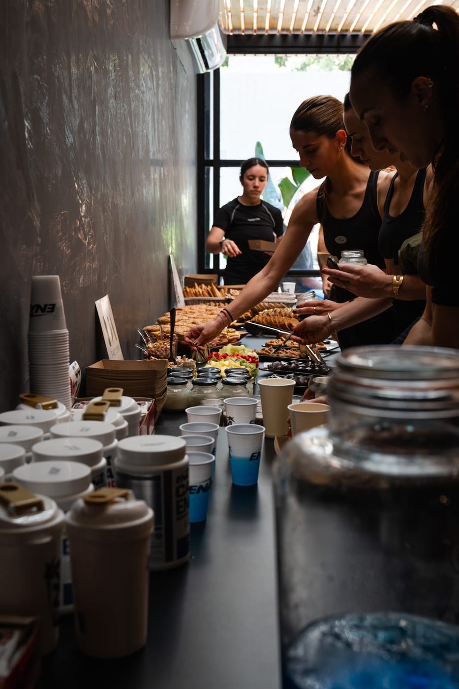 Estacion de coffee break con vasos de cafe, dispensador de agua saborizada y mesa de mini bocados dulces y salados en un evento