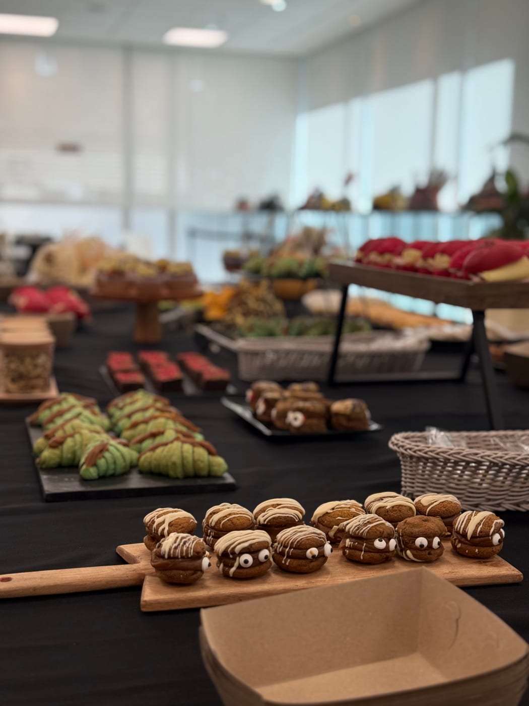 Mesa dulce de coffee break con alfajores tipo momia, medialunas verdes tematicas, brownies rojos y mini pasteleria en un evento de Halloween