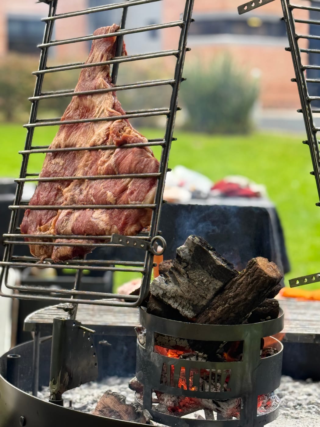 Costillar de cerdo a la estaca asándose sobre brasas de leña en un asado al aire libre