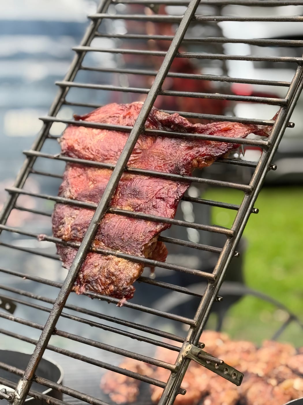 Tira de asado dorándose sobre la parrilla de estaca en un asado de evento