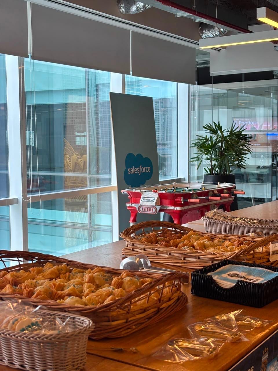 Buffet de bocaditos y empanaditas en canastas de mimbre sobre mesa de madera, en una recepcion corporativa en oficinas